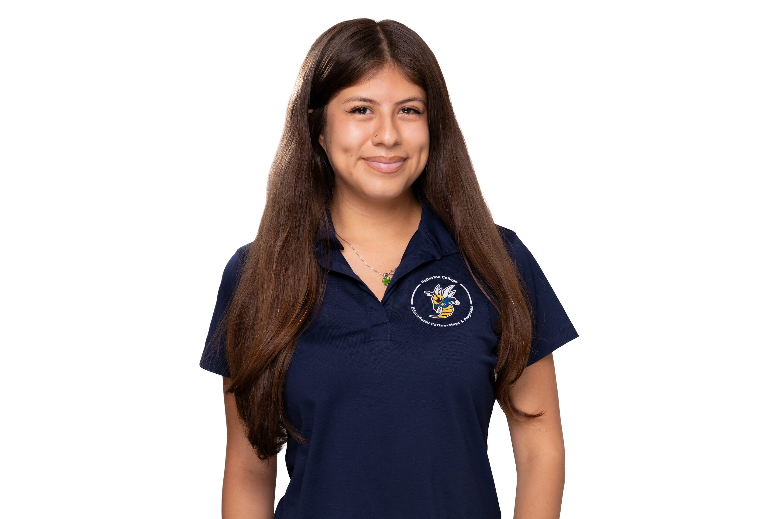 A person with long brown hair smiles while wearing a navy blue polo shirt featuring a logo on the chest.