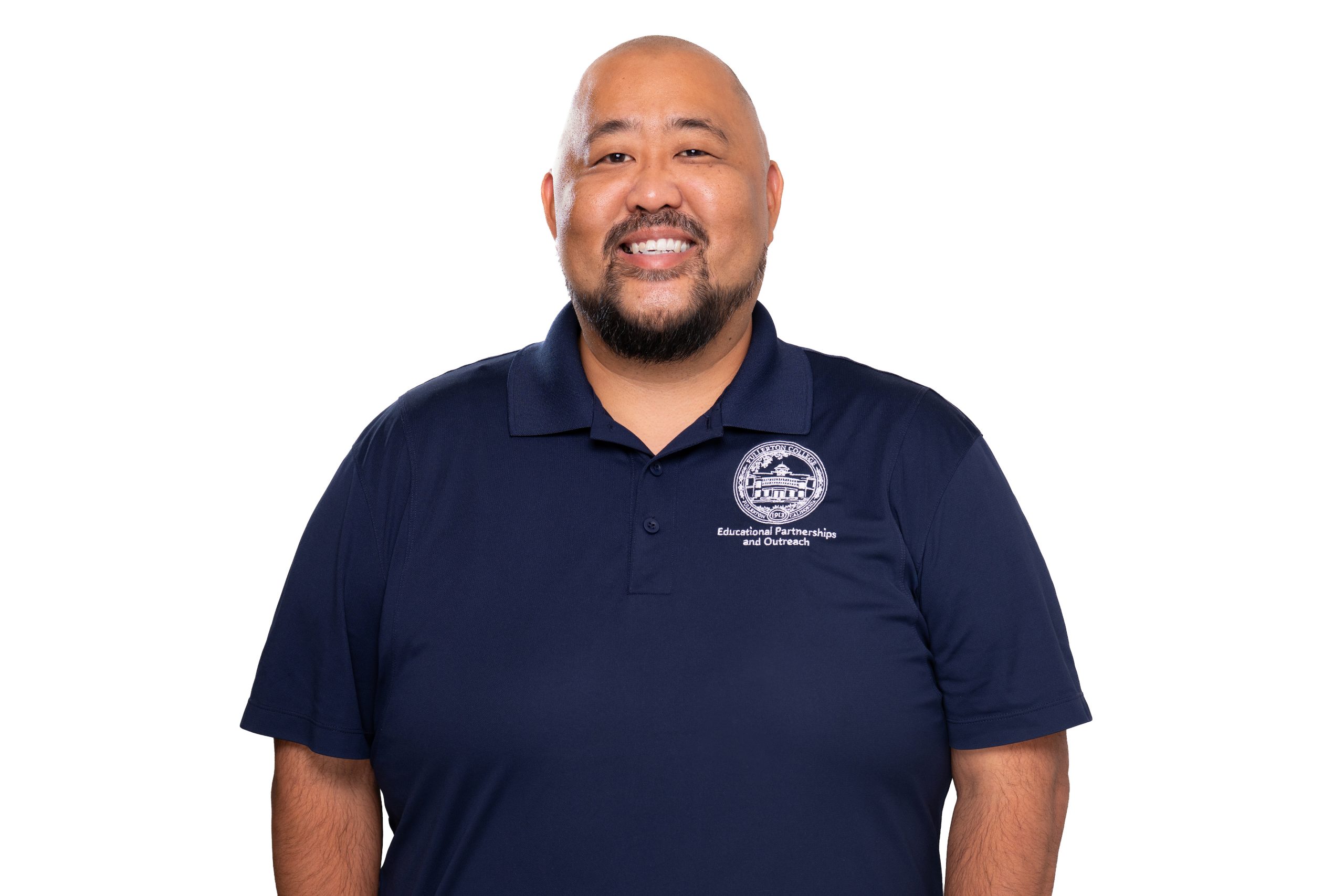 A smiling person with a beard wears a navy blue polo shirt featuring a logo and text for "Educational Partnerships and Outreach."