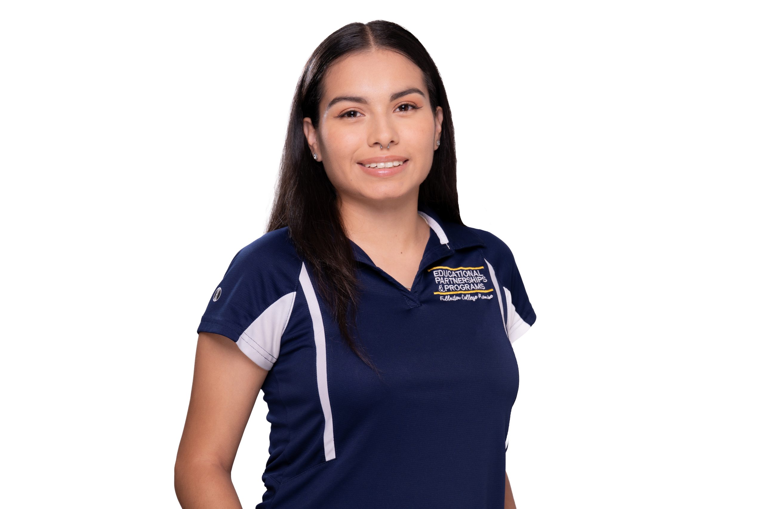 A person with long dark hair smiles while wearing a navy blue polo shirt with white accents and embroidered text on the chest.