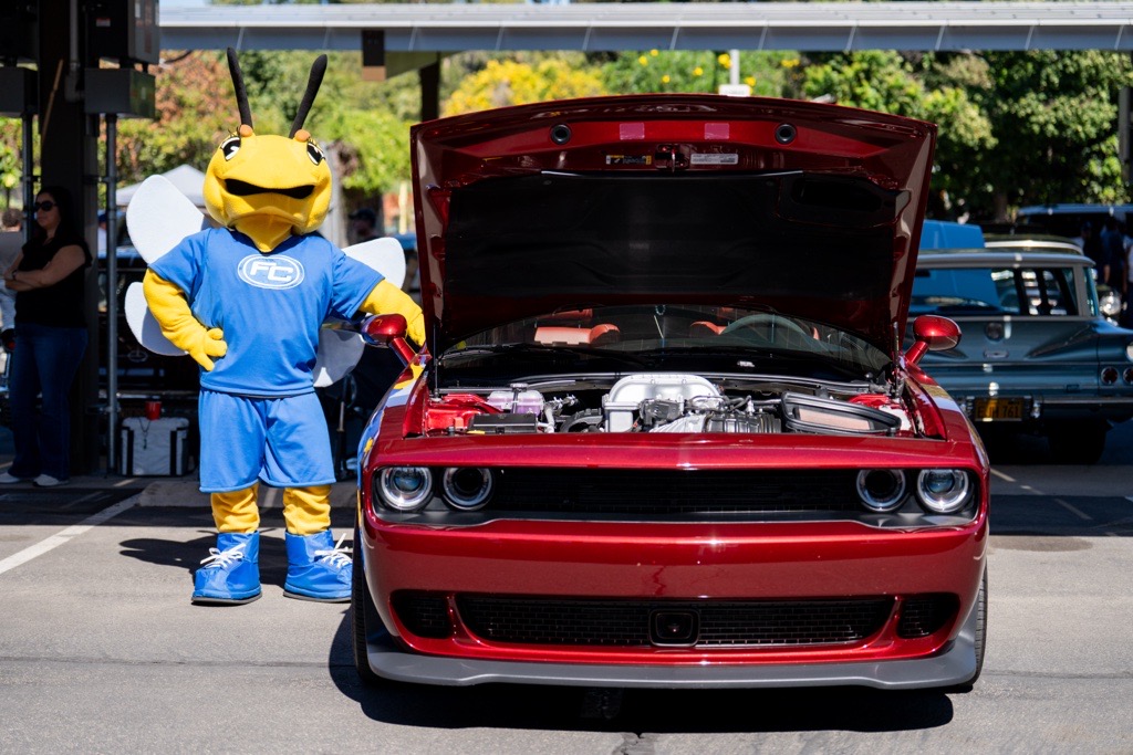 The Fullerton College mascot, Buzzy the Hornet, poses with a red car during the FC Cruisin' to College Car Show.