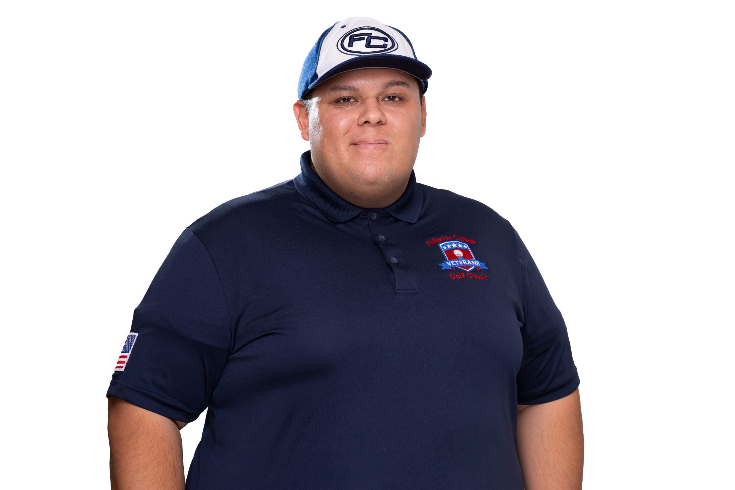 A person wearing a navy blue polo shirt with a "Veterans Golf Club" logo and a matching cap with "FC" on the front, standing against a white background.