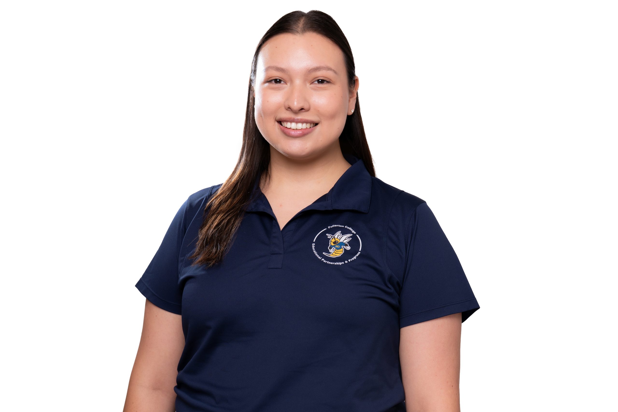 A smiling person with long dark hair wears a navy blue polo shirt featuring a circular logo with a bee design.