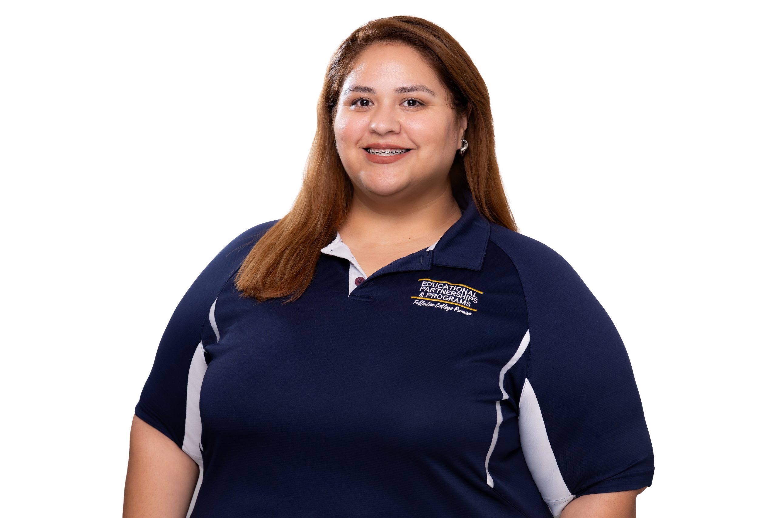 A smiling person with long brown hair wears a navy blue polo shirt featuring embroidered text on the left chest.