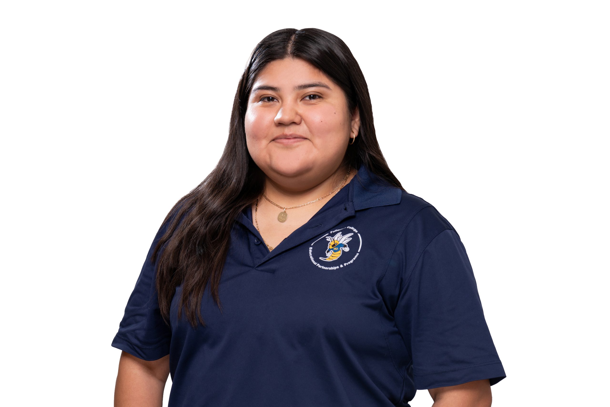 A person with long dark hair wears a navy blue polo shirt featuring a circular logo with a bee and text, standing against a plain white background.
